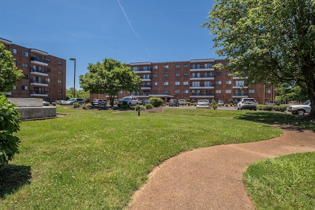 view of home's community with uncovered parking and a lawn