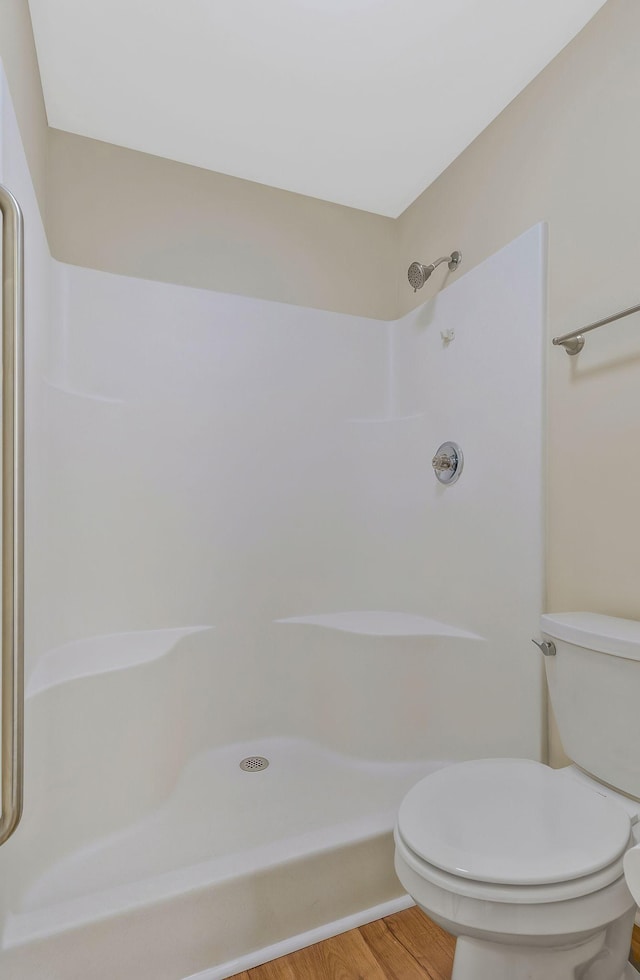 bathroom with a shower, wood finished floors, and toilet