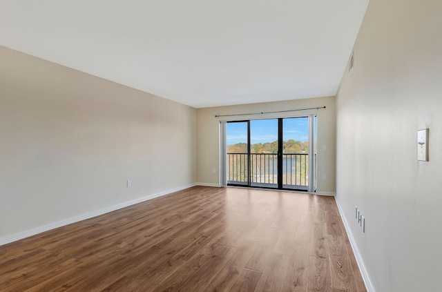 empty room with visible vents, baseboards, and wood finished floors