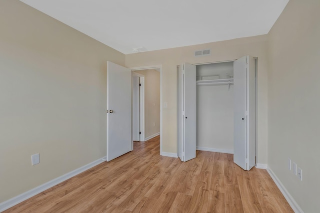 unfurnished bedroom with light wood-type flooring, a closet, baseboards, and visible vents