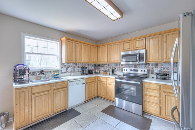 kitchen featuring light tile patterned floors, a sink, light countertops, appliances with stainless steel finishes, and backsplash