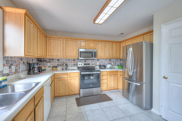 kitchen featuring tasteful backsplash, appliances with stainless steel finishes, light tile patterned flooring, light countertops, and a sink