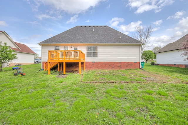 rear view of house with a shingled roof, a wooden deck, and a lawn