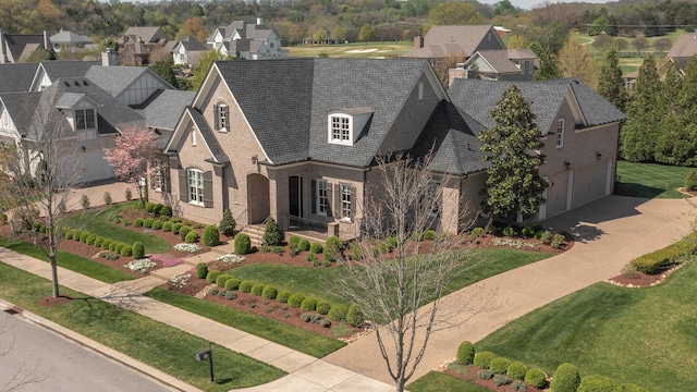 view of front of house with a chimney, concrete driveway, brick siding, a front lawn, and a residential view
