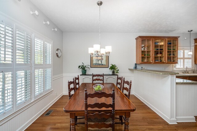 dining space with visible vents, an inviting chandelier, and wood finished floors