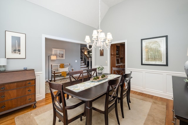 dining room with stairway, wainscoting, a notable chandelier, and light wood-style floors