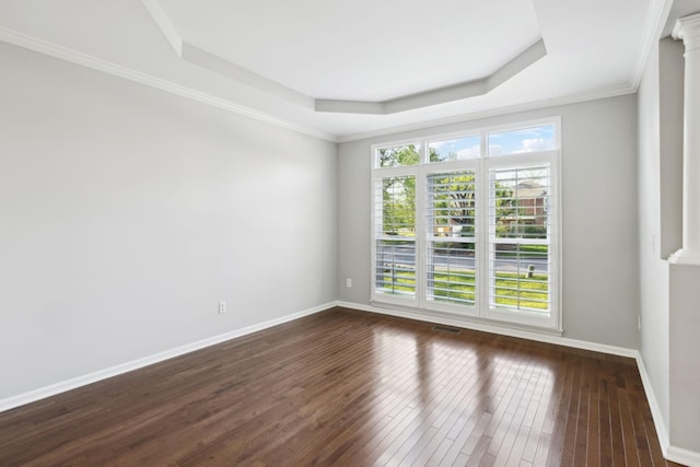 spare room featuring a raised ceiling, dark wood-style flooring, baseboards, and visible vents