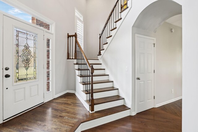 foyer featuring a wealth of natural light, arched walkways, wood finished floors, and baseboards