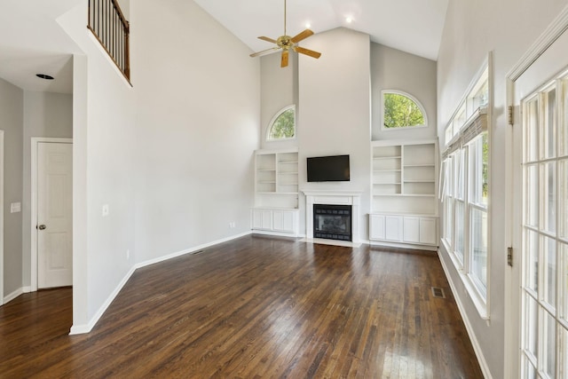 unfurnished living room featuring high vaulted ceiling, dark wood-type flooring, a ceiling fan, visible vents, and baseboards