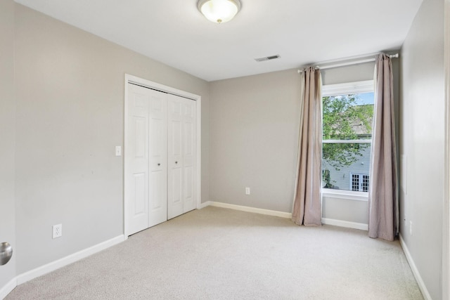 unfurnished bedroom featuring visible vents, baseboards, a closet, and light carpet