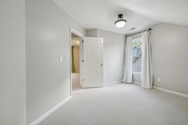 carpeted spare room featuring visible vents, baseboards, and lofted ceiling