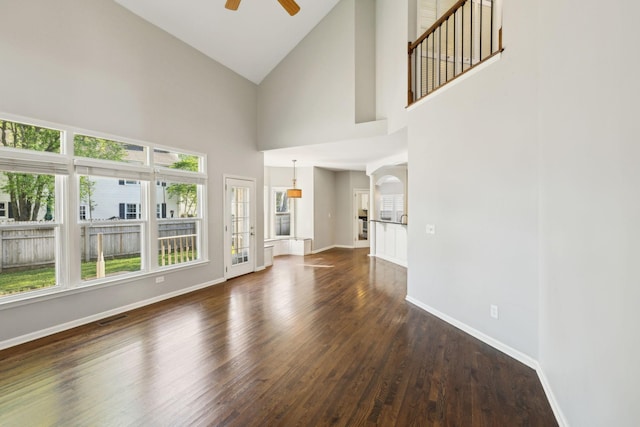 unfurnished living room featuring baseboards, visible vents, dark wood-style flooring, and a ceiling fan