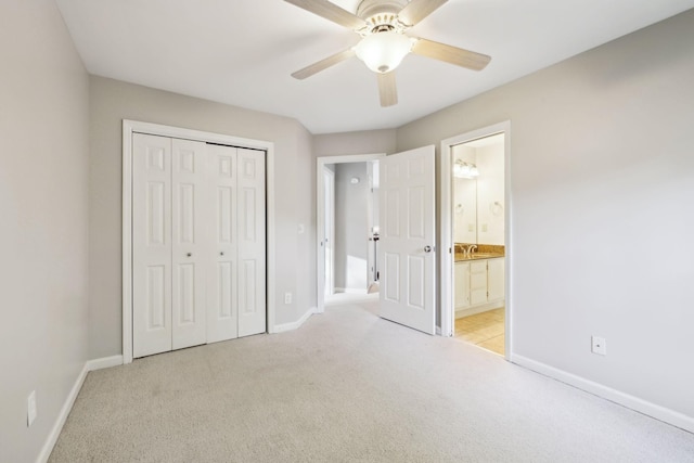 unfurnished bedroom with a closet, baseboards, ensuite bathroom, ceiling fan, and light carpet