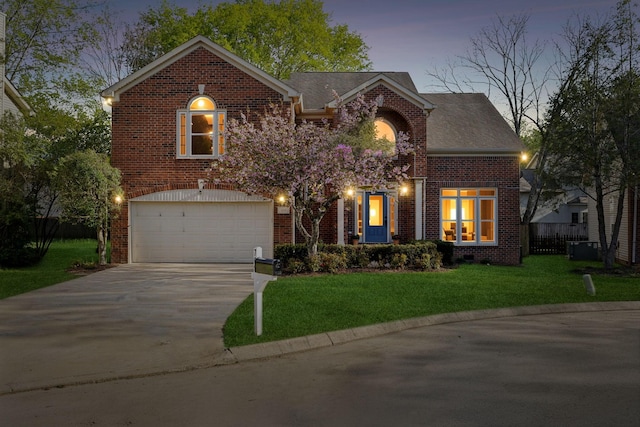 traditional home with a lawn, a garage, fence, brick siding, and driveway