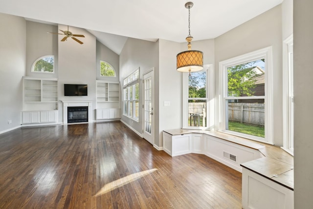 interior space with a glass covered fireplace, a wealth of natural light, visible vents, and dark wood-style floors