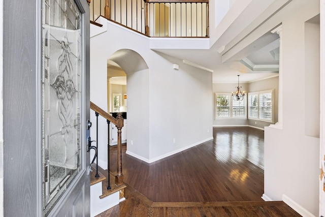 entrance foyer with a notable chandelier, baseboards, stairway, dark wood finished floors, and arched walkways