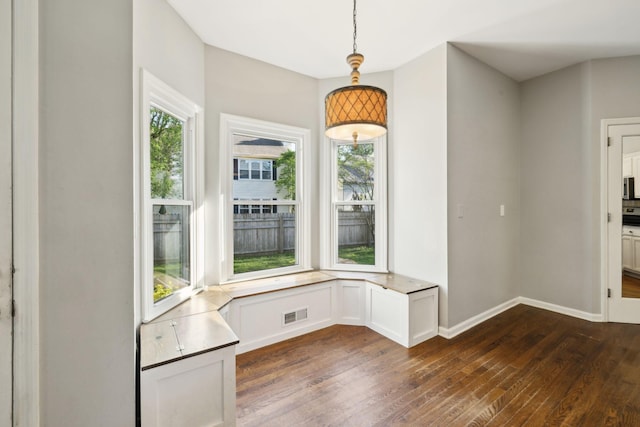 unfurnished dining area featuring baseboards, dark wood-style floors, and visible vents