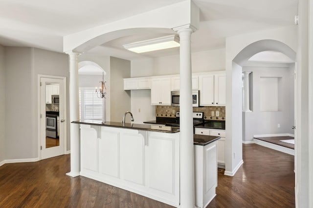 kitchen with dark wood-style floors, backsplash, dark countertops, stainless steel appliances, and a sink
