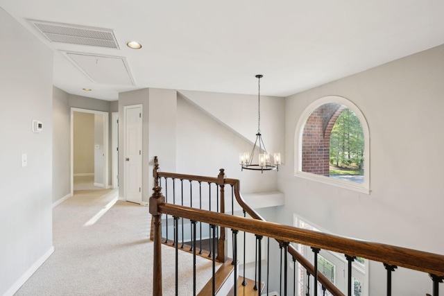 hall with baseboards, an upstairs landing, attic access, visible vents, and light colored carpet