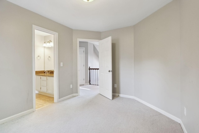 unfurnished bedroom featuring a sink, baseboards, connected bathroom, and light carpet