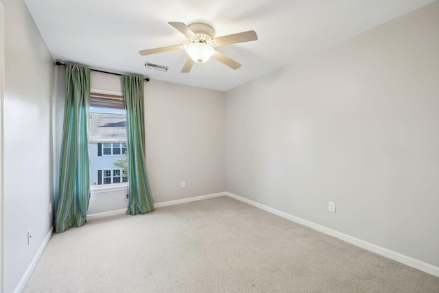 carpeted empty room with visible vents, baseboards, and ceiling fan