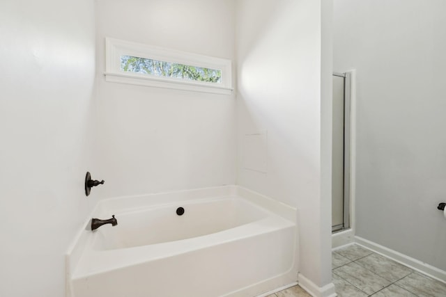 bathroom featuring a shower stall, tile patterned floors, baseboards, and a garden tub