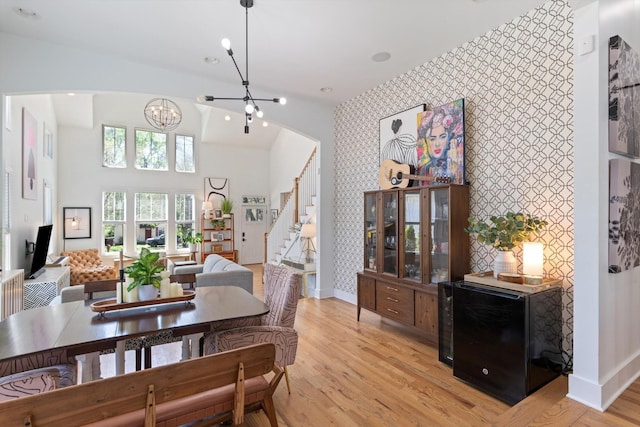 dining room with arched walkways, stairway, a notable chandelier, and wallpapered walls