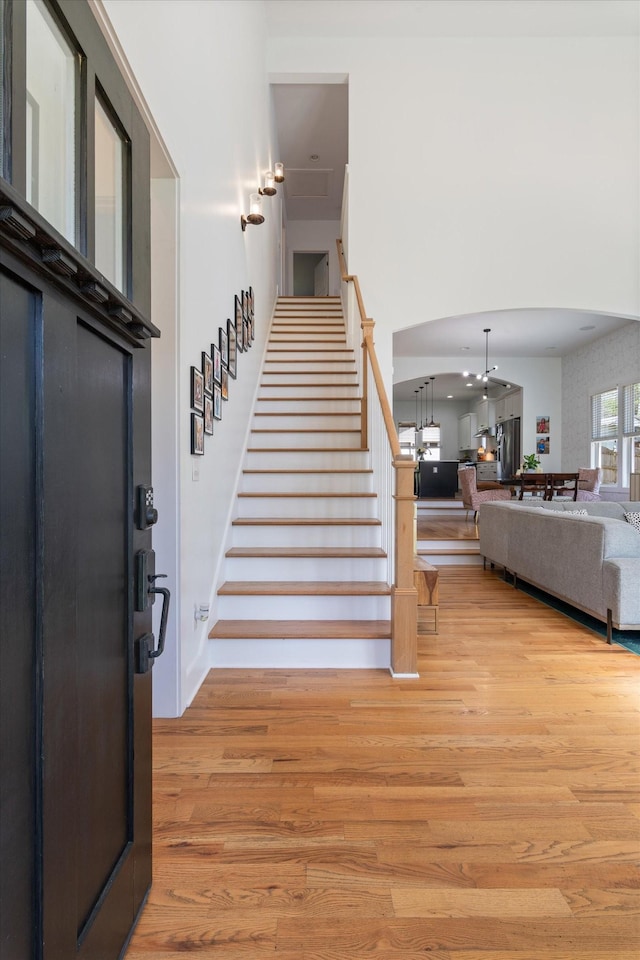 entrance foyer featuring arched walkways, light wood finished floors, and stairs