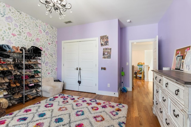 bedroom with visible vents, baseboards, a closet, a chandelier, and light wood finished floors