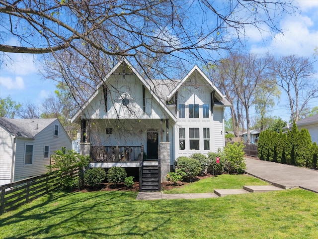 view of front facade with a porch, a front yard, and fence