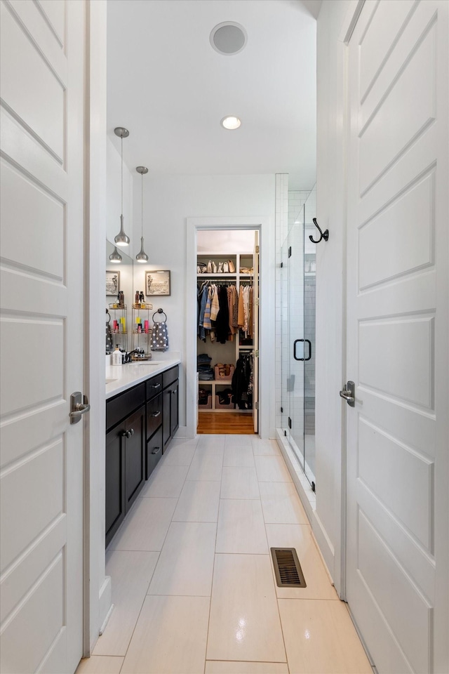 bathroom with vanity, a spacious closet, visible vents, tile patterned flooring, and a stall shower