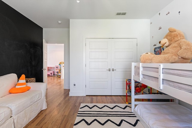 bedroom with baseboards, wood finished floors, a closet, and visible vents