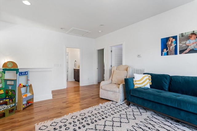 living area with visible vents, baseboards, attic access, and wood finished floors