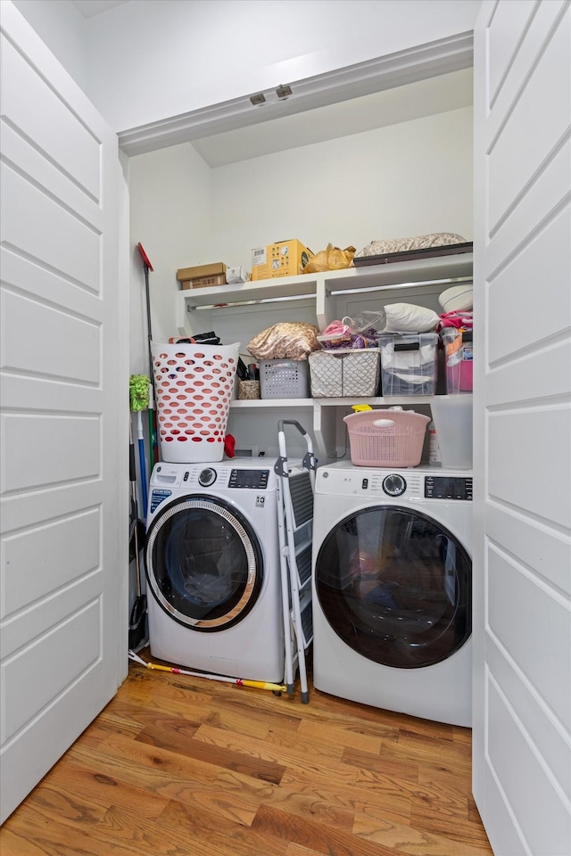 washroom with independent washer and dryer, wood finished floors, and laundry area