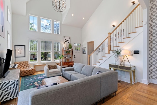 living area featuring stairway, light wood finished floors, baseboards, and an inviting chandelier