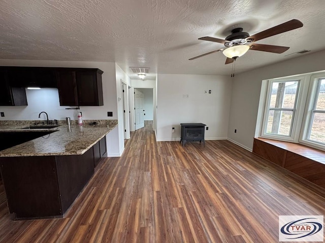 5380 Sulphur Creek Rd, Big Sandy, TN 38221 - kitchen featuring ceiling fan, a wood stove, light stone counters, a sink, and dark wood-style floors