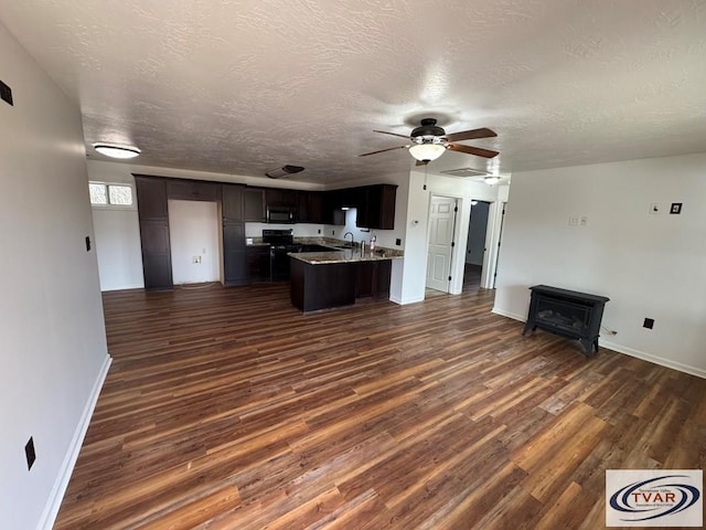 5380 Sulphur Creek Rd, Big Sandy, TN 38221 - kitchen with dark wood-style flooring, black microwave, open floor plan, a peninsula, and a wood stove