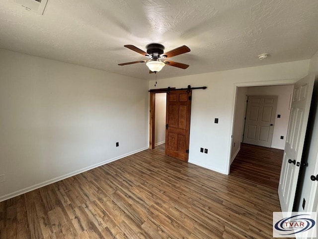 5380 Sulphur Creek Rd, Big Sandy, TN 38221 - unfurnished bedroom featuring wood finished floors, baseboards, and a barn door