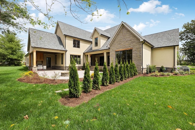 521 Mansion Dr, Brentwood, TN 37027 - rear view of property featuring a patio, roof with shingles, stucco siding, stone siding, and a lawn