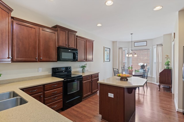 kitchen with an inviting chandelier, dark wood finished floors, black appliances, light countertops, and a sink