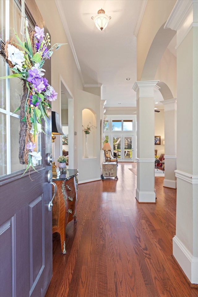foyer entrance with decorative columns, arched walkways, crown molding, and wood finished floors