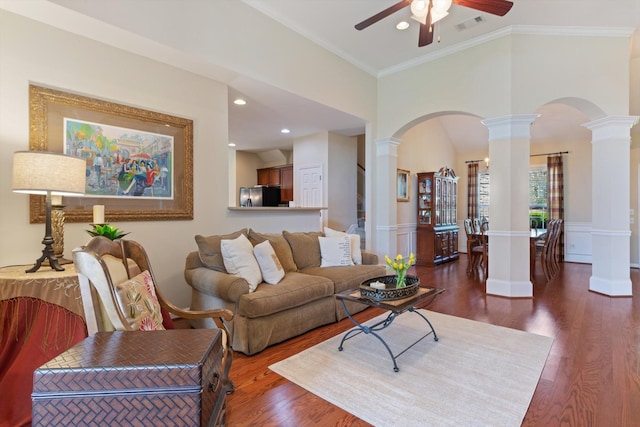 living area featuring decorative columns, arched walkways, wood finished floors, and ceiling fan