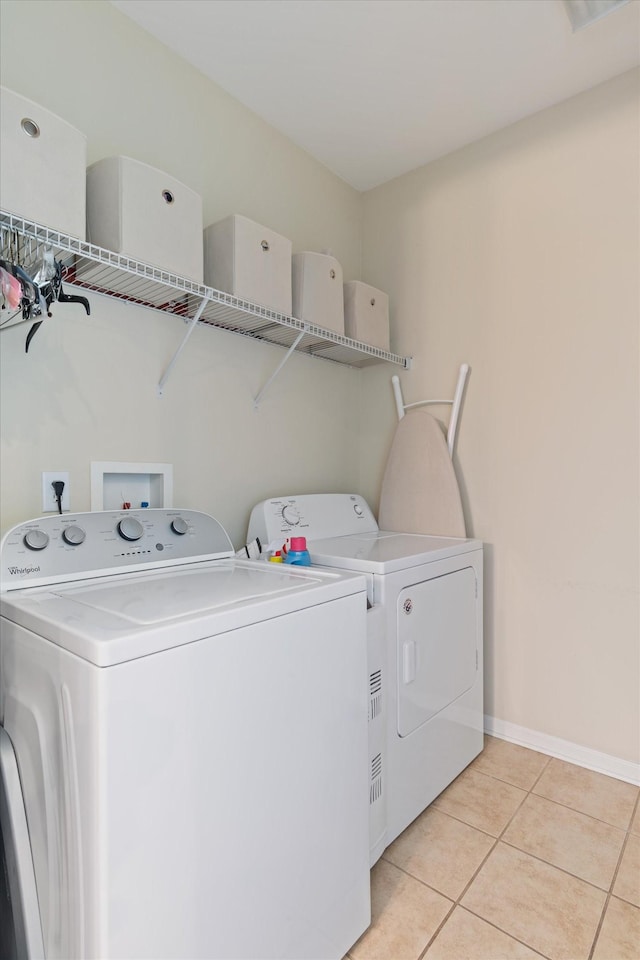 clothes washing area featuring laundry area, light tile patterned floors, baseboards, and washing machine and dryer