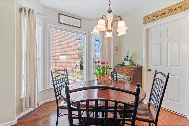 dining space with baseboards, an inviting chandelier, and wood finished floors