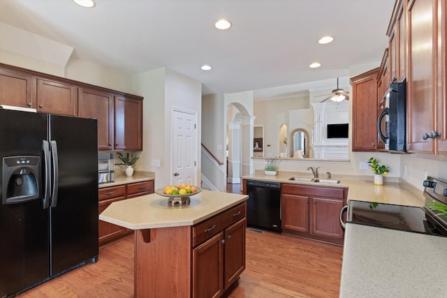 kitchen with light countertops, light wood finished floors, a sink, and black appliances