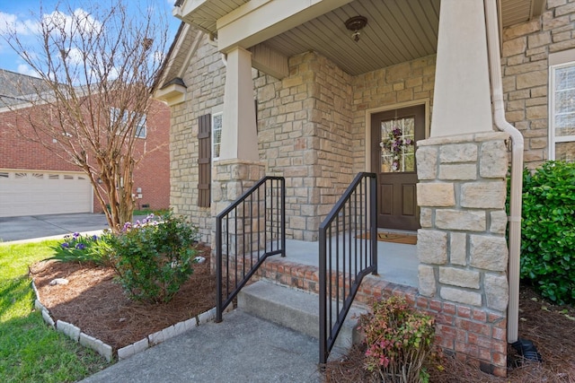 doorway to property with driveway, stone siding, and a garage