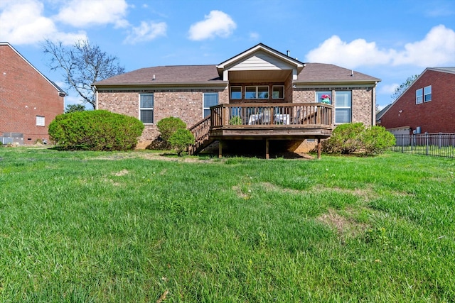 back of house featuring brick siding, a wooden deck, fence, and a lawn