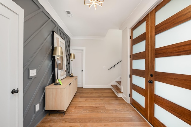 interior space with visible vents, baseboards, crown molding, light wood finished floors, and stairs