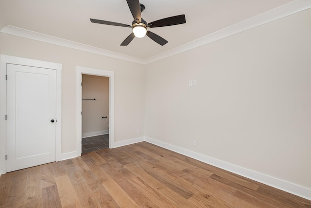 empty room featuring baseboards, light wood-type flooring, crown molding, and ceiling fan