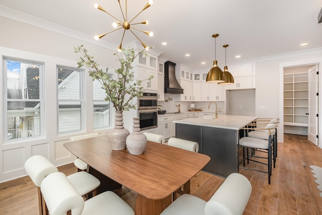 dining room with light wood-style flooring, a chandelier, ornamental molding, and recessed lighting